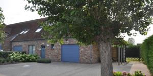 a brick house with a blue garage at de Graspieper in Oostduinkerke
