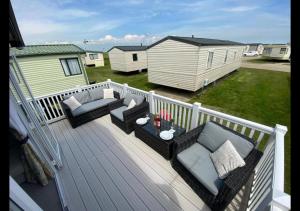 a deck with couches and chairs on a house at MP413 - Camber Sands Holiday Park - Close to Facilities - Free Wifi - Sleeps 8 - Large Decking in Camber +35 photos