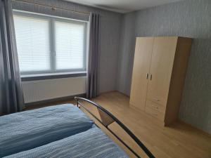 a bedroom with a bed and a cabinet and a window at NEU! Ferienwohnung Doris Ostfriesland in Großefehn 
