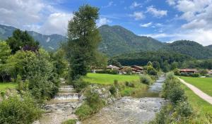 een rivier in een veld met bergen op de achtergrond bij Ferienwohnung SonnenHain in Unterwössen