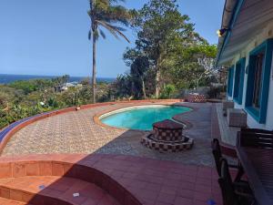 Una piscina con una mesa y sillas al lado de una casa. en Paradiso, en Port Shepstone