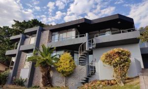 Una casa en blanco y negro con árboles delante. en Gordon's Bay Sunset View, en Ciudad del Cabo