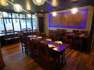 a restaurant with wooden tables and chairs and a large window at The Oasis Hotel in Harlow