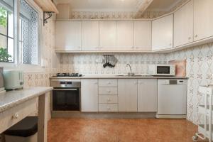 una cocina con armarios blancos y electrodomésticos blancos en Casa Linda, en Guaro
