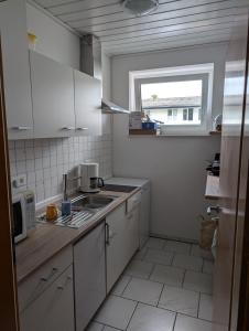 イッベンビューレンにあるFerienwohnung Monteurzimmer Ibb DSBTの白いキャビネット、シンク、窓付きのキッチン