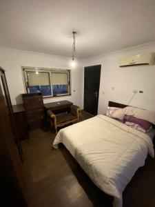 ein Schlafzimmer mit Bett, Schreibtisch und Fenster in der Unterkunft Elegant Villa in Hyde Park in New cairo