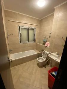 ein Badezimmer mit Badewanne, Toilette und Waschbecken in der Unterkunft Elegant Villa in Hyde Park in New cairo