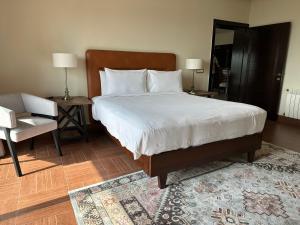 a bedroom with a large bed with a chair and a table at Mariano By Goldfinch in Islamabad