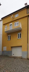 a yellow building with a balcony and a garage at Casa Amarela - Serra da Estrela Portugal in Verdelhos