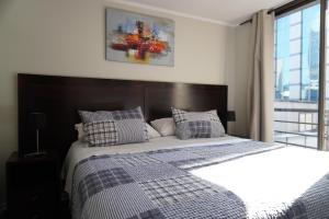 a bedroom with a large bed with blue and white sheets at San Ignacio Suite Apartments in Santiago