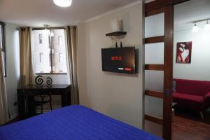 a bedroom with a bed and a tv on the wall at San Ignacio Suite Apartments in Santiago