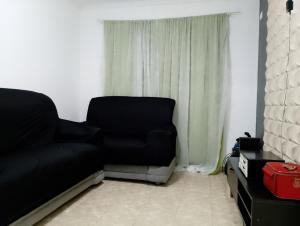 a black couch in a living room with a window at Apto Domeni, seu conforto a 10 min da praia! in Praia Grande