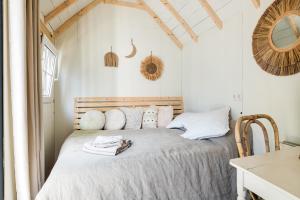 a bedroom with a bed with white sheets and a mirror at Tiny house Zaandam in Zaandam