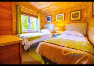 1 Schlafzimmer mit 2 Betten in einer Holzhütte in der Unterkunft Rainbow Petty - Romney Marsh, Kent in Brookland