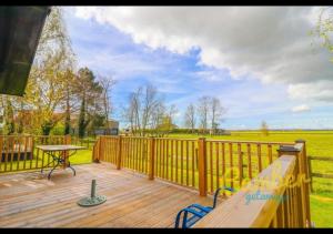 eine Holzterrasse mit einer Bank und einem Tisch darauf in der Unterkunft Rainbow Petty - Romney Marsh, Kent in Brookland