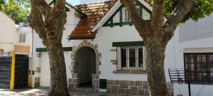 a white house with a window and two trees at Maui Hostel in Mar del Plata