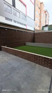 ein Backsteingebäude mit grünem Rasen davor in der Unterkunft Nuevo Loft cerca a la Embajada Americana, Corferias y Agora in Bogotá