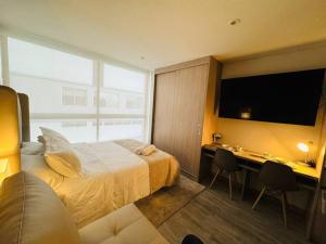 ein Hotelzimmer mit Bett, Schreibtisch und Fernseher in der Unterkunft Nuevo Loft cerca a la Embajada Americana, Corferias y Agora in Bogotá