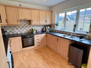 eine Küche mit Holzschränken und Spüle und einem Fenster in der Unterkunft Waterfoot House in Derry Londonderry + 16 Fotos