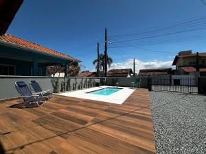 un patio con 2 sedie e una piscina di BS01- Casa com Piscina Aquecida e Churrasqueira a Balneário Barra do Sul