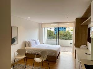 ボゴタにあるAvanzza apartamentos cerca del Dorado by Wellcomeのベッドルーム1室(ベッド1台、椅子2脚付)