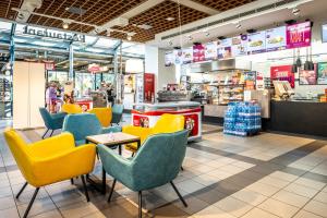 a restaurant with yellow chairs and tables in a store at Serways Hotel Feucht Ost in Feucht