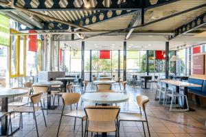 a restaurant with tables and chairs and windows at Serways Hotel Feucht Ost in Feucht