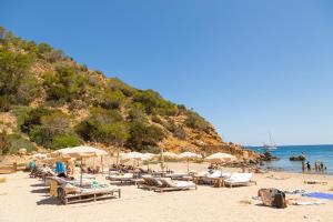 plaży z kilkoma leżakami i parasolami w obiekcie Large Villa on Ibiza West Coast with pool & sunset view - Nirvana w mieście Cala Tarida