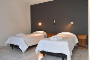 two beds with white sheets in a room at Gran hotel argentino in Villa Carlos Paz
