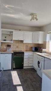 a kitchen with white cabinets and a green dishwasher at Doncaster-House-Sleeps8-Parking-Garden in Doncaster