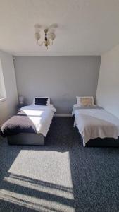 a bedroom with two beds and a chandelier at Doncaster-House-Sleeps8-Parking-Garden in Doncaster