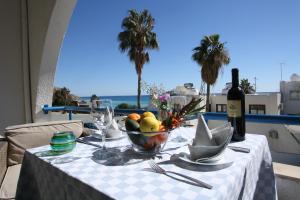 a table with a bowl of fruit and a bottle of wine at Pissouri Beach Apartments in Pissouri