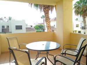 a table and chairs on a balcony with palm trees at Résidence luxe à la mer in Roda