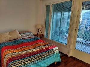 a bedroom with a bed with a colorful blanket and windows at Kolmio, parvekkeet, meri, sauna ja keskustassa! in Helsinki