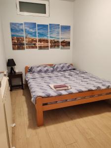 a bed in a room with four paintings on the wall at Cozy green house (free parking spot) in Belgrade