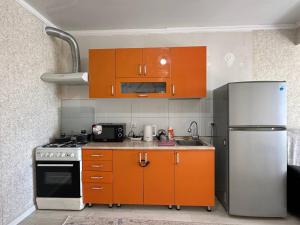 比什凯克1bedroom Royal on Zhumabeka 232的厨房配有橙色橱柜和不锈钢冰箱