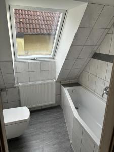 a bathroom with a tub and a toilet and a window at Ferienwohnung für vier Personen in Helmstadt