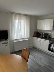 a kitchen with a wooden table and a kitchen with white cabinets at Ferienwohnung für vier Personen in Helmstadt