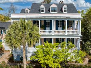 a white house with a palm tree in front of it at The Ashley Veranda King Suite with Breakfast in Charleston