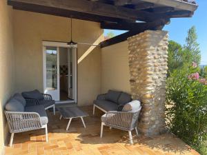 a patio with wicker chairs and a stone pillar at Villa Kéana en Sud Ardèche, avec piscine in Lachapelle Sous Aubenas