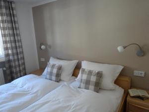 a bed with white sheets and pillows in a room at Ferienwohnungen im Färberhaus in Fischen