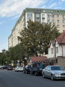 比什凯克1bedroom Royal on Zhumabeka 232的一条街道,汽车停在一个大建筑前 更多2张照片