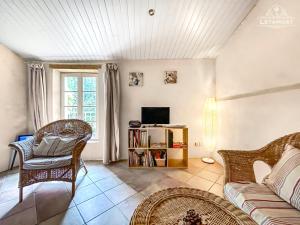 een woonkamer met een bank en een tv bij Charme rustique avec jardin privé "Au Pastel" in Soupex