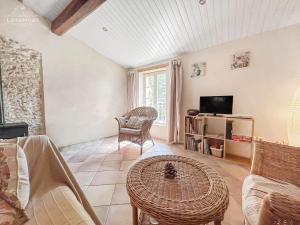 een woonkamer met een tafel en een tv bij Charme rustique avec jardin privé "Au Pastel" in Soupex