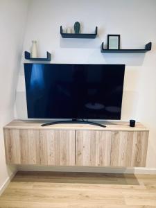 einen Flachbild-TV auf einem hölzernen Entertainment-Center in der Unterkunft Appartement design et cozy à port cergy in Cergy