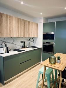 eine Küche mit grünen Schränken und einem Holztisch in der Unterkunft Appartement design et cozy à port cergy in Cergy