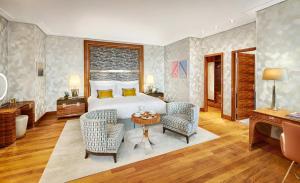 a bedroom with a bed and two chairs and a table at Mandarin Oriental, Munich in Munich