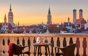 a table on a balcony with a view of a city at Mandarin Oriental, Munich in Munich