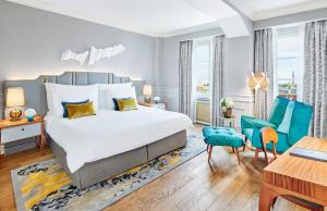 a bedroom with a large bed and blue chairs at Mandarin Oriental, Munich in Munich