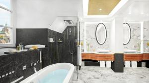 a bathroom with a tub and two sinks and mirrors at Mandarin Oriental, Munich in Munich
